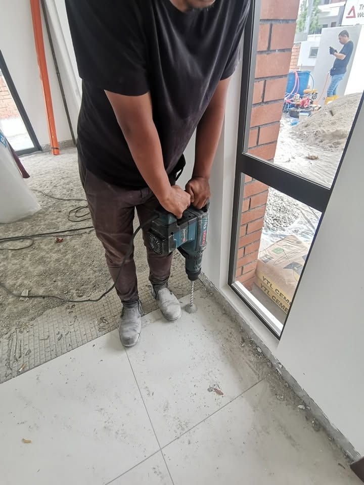 师傅在施工中建筑的门口位置,沿地台边缘钻孔。